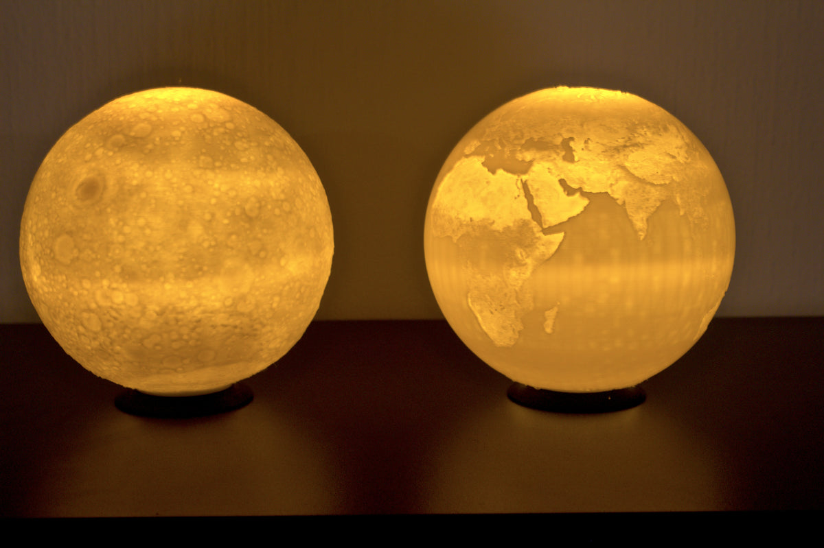 Geschenkset Mondlampe und Erdkugel-Lampe: beide Lithophane-Kugeln nebeneinander, von innen beleuchtet